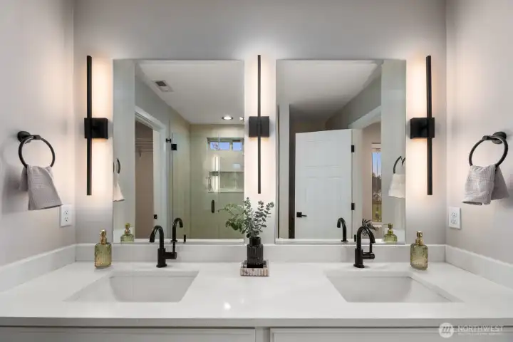 Bright primary bathroom featuring a wide dual vanity with two sinks, large mirrors, and modern wall lighting that evenly illuminates the space. The clean design and spacious counter area create a functional and comfortable daily routine space.