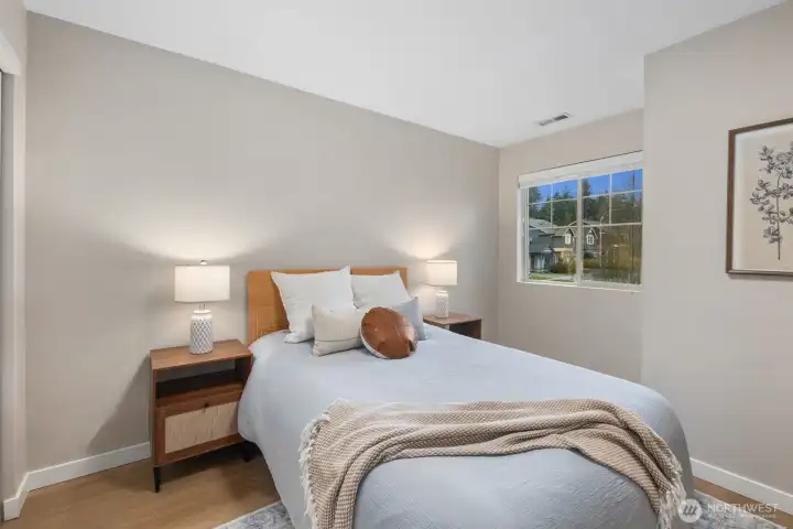 Spacious bedroom featuring a large window and generous wall space for flexible furniture placement. The soft color palette and natural light create a comfortable, airy atmosphere.