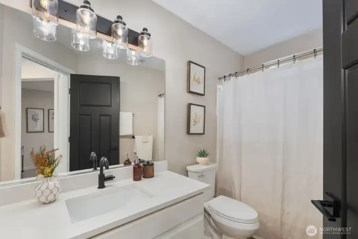 Bright full bathroom with wide vanity, modern lighting, and a clean shower and bath area. Thoughtfully designed for everyday functionality with a neutral palette that keeps the space light and welcoming.