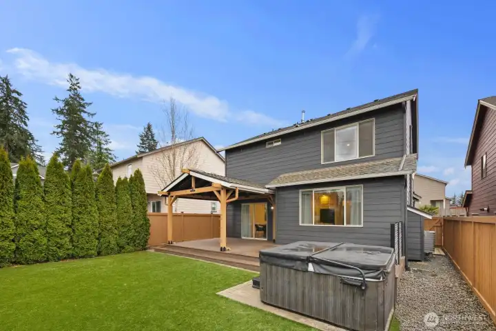 Wide backyard view highlighting the home’s covered patio area, open green space, and surrounding fencing for added privacy. The outdoor layout provides flexible space for relaxation, gatherings, and outdoor living.