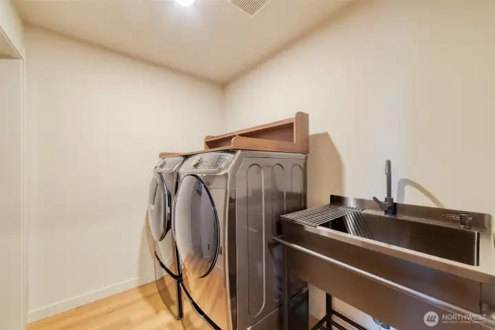 Generously sized full-capacity washer and dryer with accompanying utility sink on the main floor.