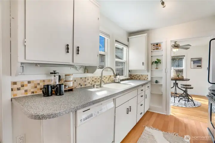 The kitchen offers good prep space, laminate flooring, and built-in shelving for added function.