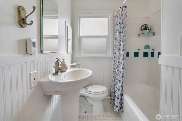 The full bathroom includes a pedestal sink, ceramic tile, and classic wainscoting—plus a tankless water heater for added efficiency.