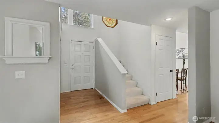 Large, welcoming foyer with vaulted ceilings, hardwood floors and large windows.