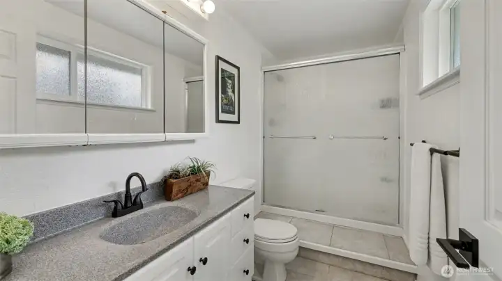 Primary bathroom features Corian countertops, tile flooring, and modern fixtures.