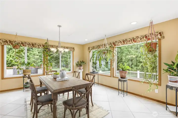 The sunroom/dining area is bathed in light throughout the day with large pane windows bringing the outdoors, in.