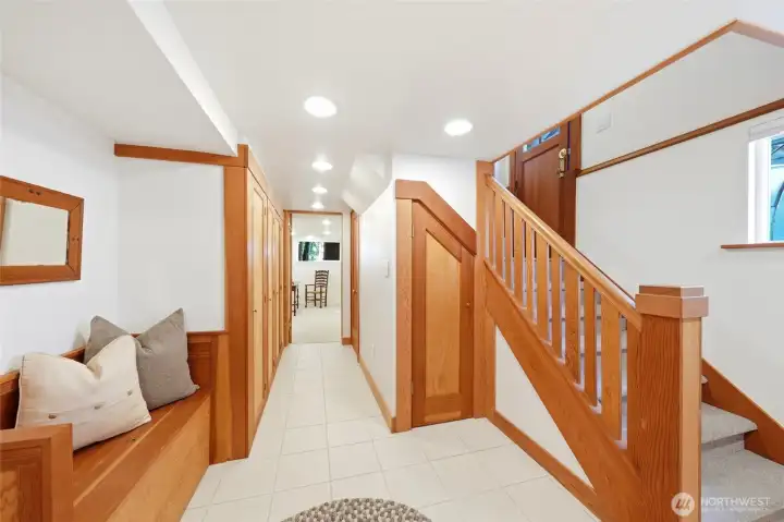 Basement foyer with cedar seat with storage and a closet with hooks for coats and additional storage
