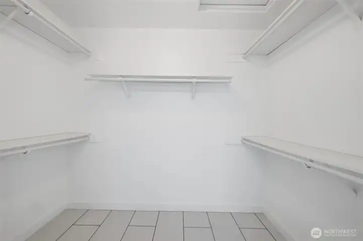 View of large walk-in closet with many built in shelves.