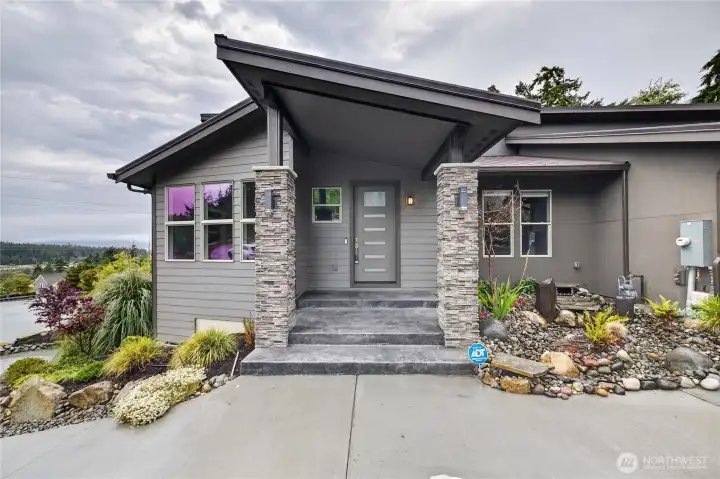 A striking covered entry with soaring rooflines, stacked stone columns, and beautifully landscaped grounds creates an unforgettable first impression of this thoughtfully designed modern home. A striking covered entry with soaring rooflines, stacked stone columns, and beautifully landscaped grounds creates an unforgettable first impression of this thoughtfully designed modern home.