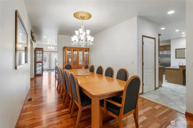 Large dining room with Cherry Hardwood Flooring, hanging Brass and Glass Chandelier, custom built Solid Oak table seats 12 & Solid Oak Hutch and built in Accent Lighted Glass Display Shelving.