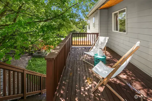 private deck with shade and stairs leading down to a fully fenced yard.