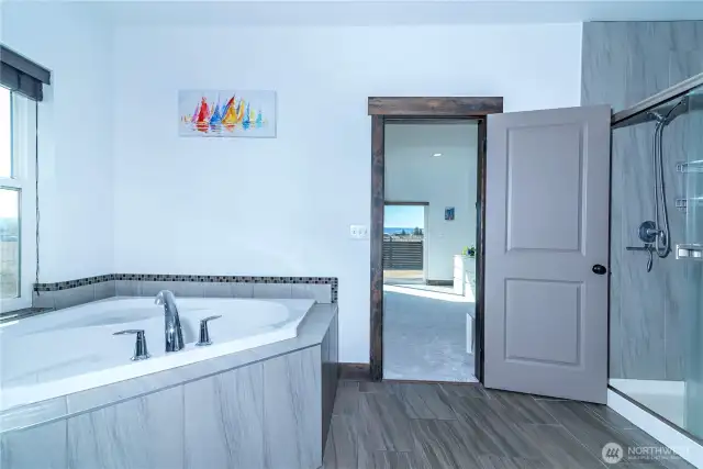 The spa-like primary en-suite offers a soaking tub, shower, and a spacious walk-in closet.