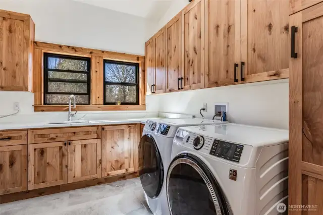 Large utility room features tons of extra cabinets and plenty of counter space, with stainless steel sink.