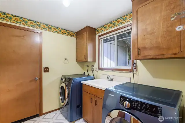 Spacious laundry room with a large utility sink is also a mudroom, with this door leading to the garage. Easy grocery route! Washer and dryer are included.