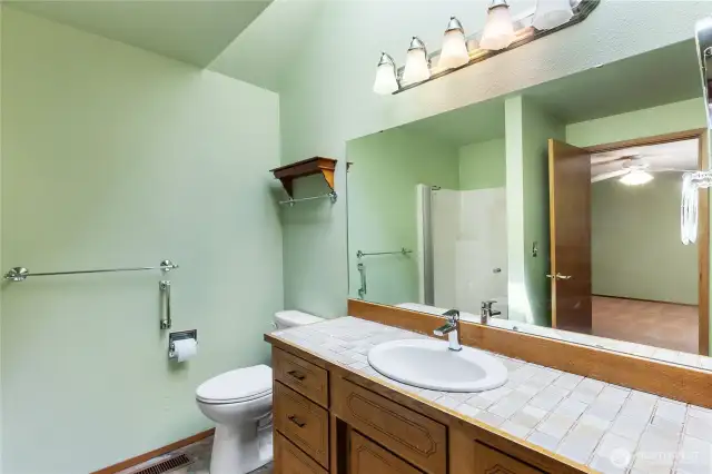 Primary ensuite bath with tile countertops and shower