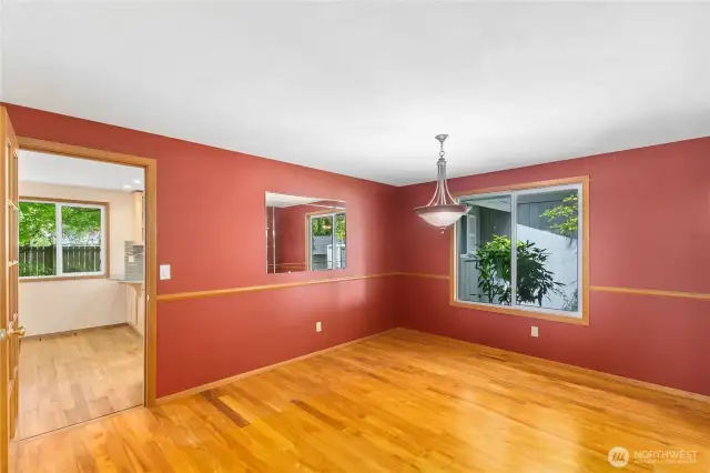 The dining room empty. Handsome wood flooring and chair rail. Glass pane door leads to kitchen for convenient serving and the ability to close it off.