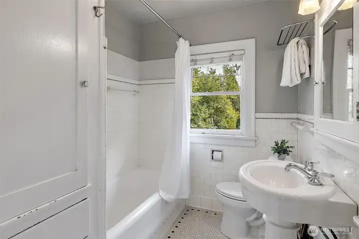 Upstairs full bath with bult in storage and original hex tile on the floor