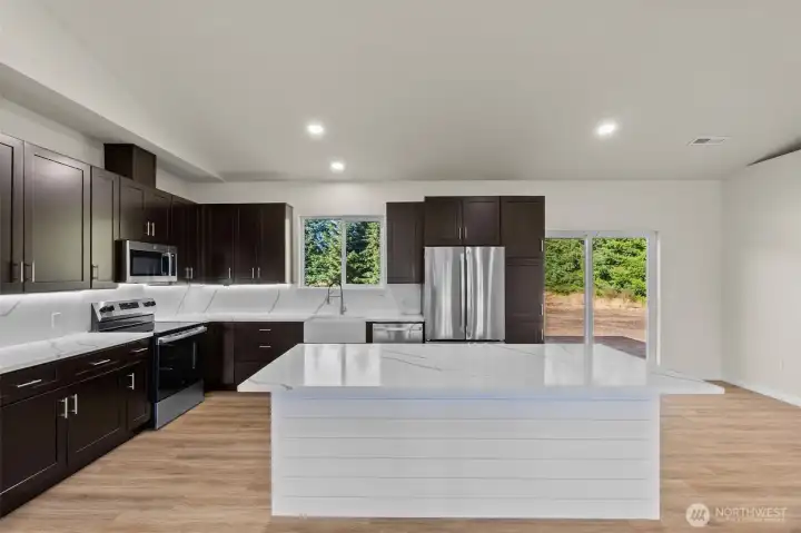 Note the under cabinet lighting, Stainless steel appliances, and barstool seating area.