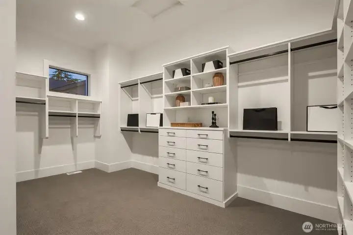 A generously proportioned primary walk-in closet crafted to accommodate an extensive wardrobe, offering effortless organization and luxury storage space for all your clothing, shoes, and accessories — your personal dressing sanctuary.