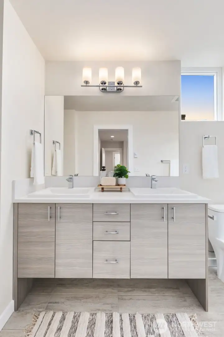 Photo of a previous model home. Primary Bathroom complete with custom built in shelving, double vanity and large walk in shower.  Natural light and tiled floors.