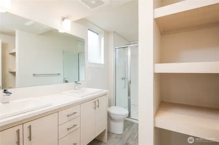 Photo of a previous model courtyard home. Primary Bathroom complete with custom built in shelving, double vanity and large walk in shower.  Natural light and tiled floors.