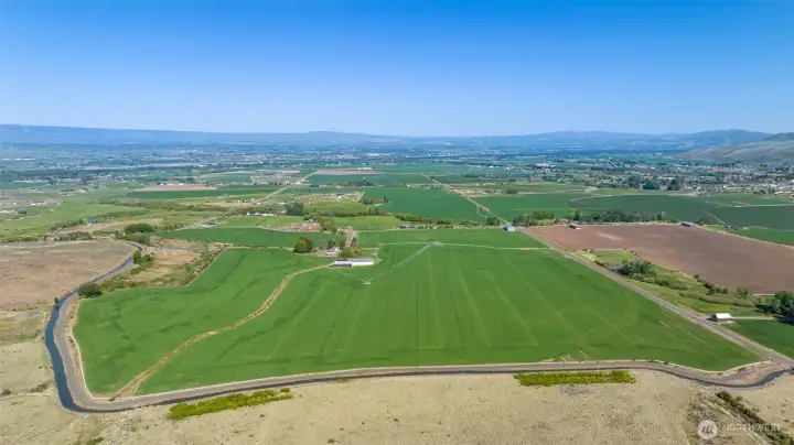Expansive aerial view showcasing all 158+ acres of this remarkable Ellensburg ranch, captured looking east toward the city and framed by sweeping mountain vistas. A rare perspective that highlights the scale, open space, and stunning natural beauty of the surrounding landscape.