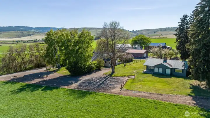 Southwest-facing view featuring the guest home in the foreground, with the main residence and additional outbuildings set beyond. This angle captures the thoughtful layout of the property, showcasing the versatility of multiple structures against a backdrop of open land and big sky views.