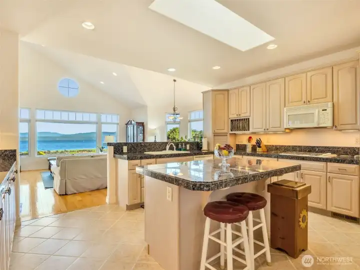 To the right of the entrance, Gourmet kitchen with granite countertops, center island, abundant cabinetry, and stunning water views.