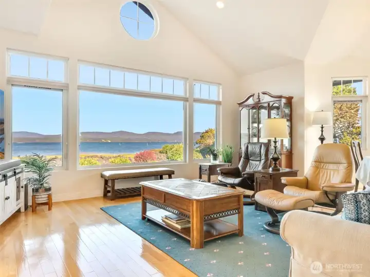 Open great room filled with natural light and framed by walls of windows overlooking the water.