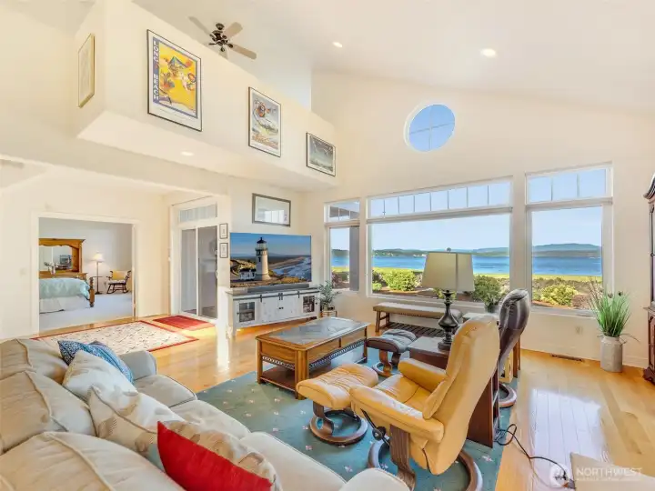 Spacious living room with vaulted ceilings, expansive windows, and uninterrupted bay views.