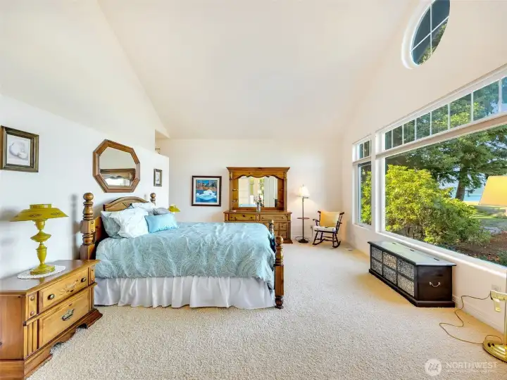 Spacious primary suite with abundant natural light, vaulted ceilings, and tranquil water views.
