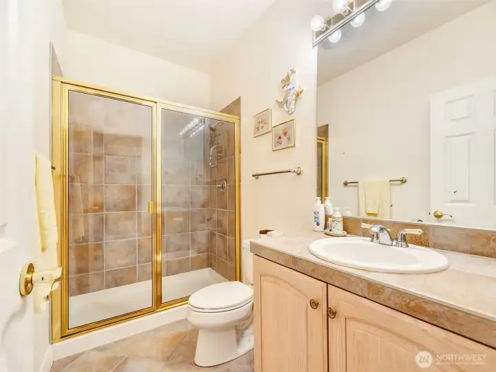 Convenient guest bathroom near the guest bedroom and entrance with a walk-in shower and modern vanity.