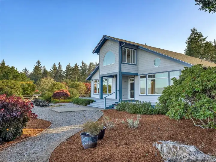Rear exterior facing the Willapa Bay, highlighting the home's thoughtful design, mature landscaping, and private setting.