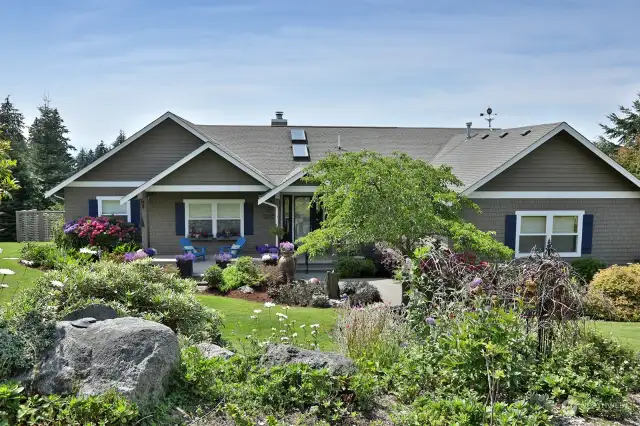 Lush landscaping surrounds this one level craftsman style home.