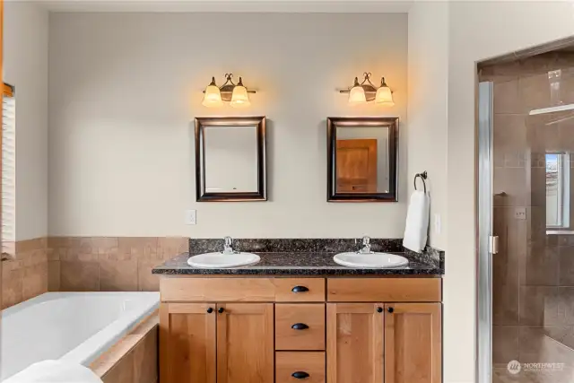 Primary Bath #1 features a custom double vanity, walk in tile shower, toilet and soaking tub.