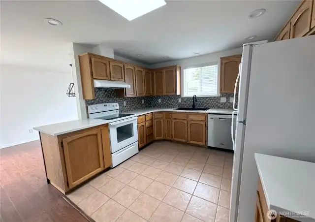 The light filled kitchen has white quartz counter tops and a lot of cupboard space. It is open to the dining room.