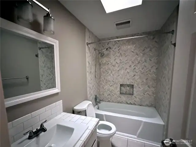 Stylish second bathroom with bath tub and skylight