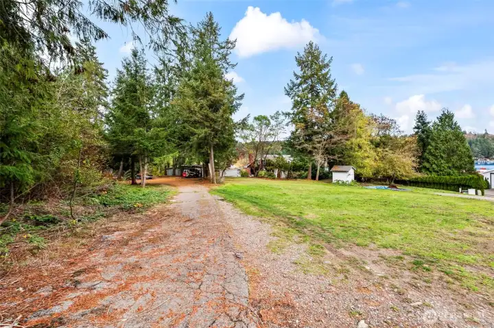 Driveway into the property from the shared drive.  The little structure in the orchard is the shared 3 party well - in great condition.