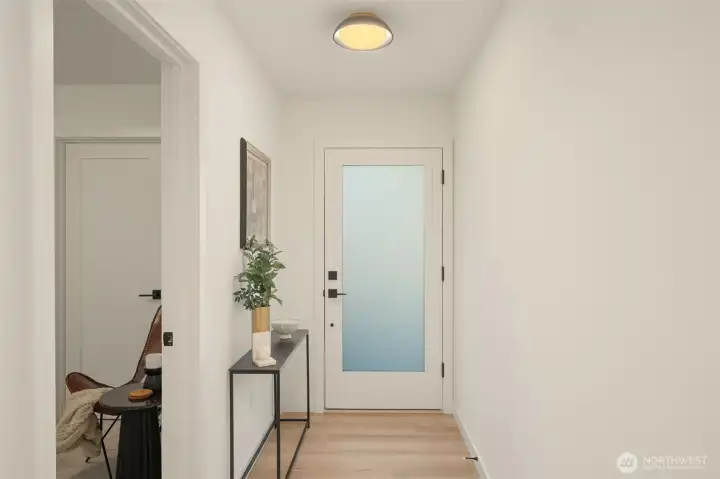 A frosted glass entry door floods the entrance with soft, natural light while maintaining privacy.