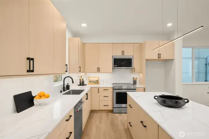 The open floor plan leads directly into a bright kitchen, anchored by light wood cabinetry and crisp quartz countertops.