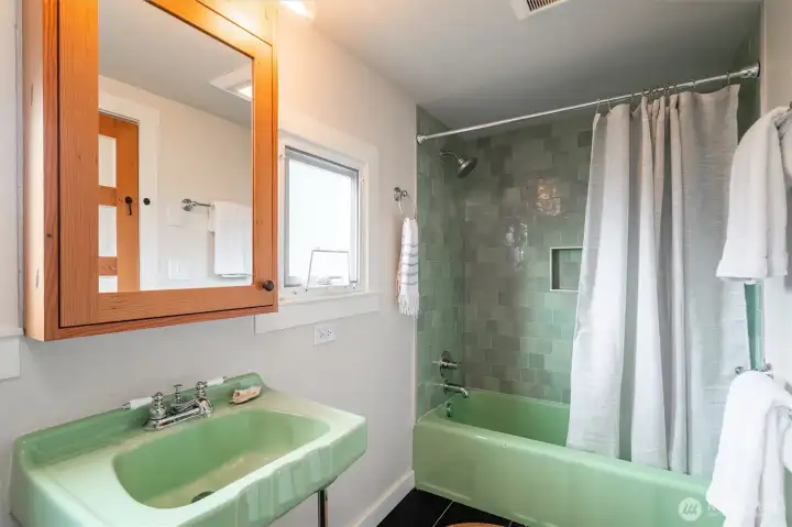 The remodeled bathroom has a gorgeous new tile surround, while keeping some en vogue vintage fixtures.