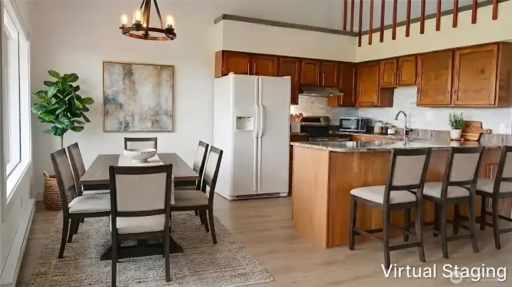 Bright, open kitchen with ample cabinetry, generous counter space, and a breakfast bar, seamlessly flowing into a dedicated dining area and enhanced by high ceilings for an airy feel.