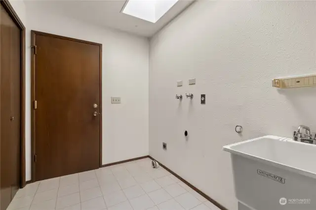 Large laundry room with skylight leads to double car garage with loads of storage