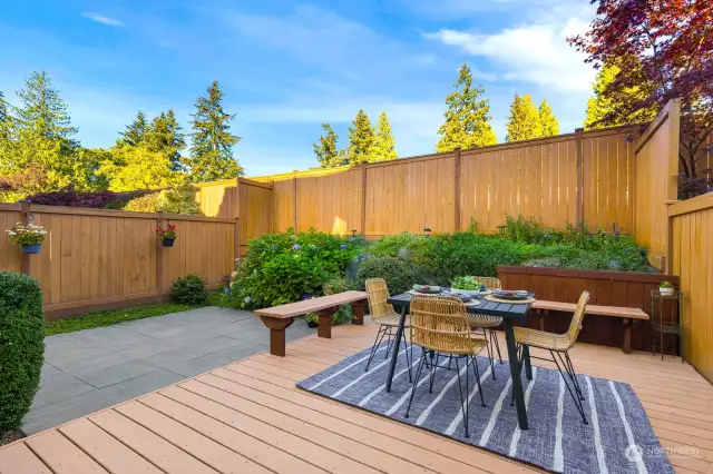 Elevate your outdoor experience with a dedicated dining area, set against a backdrop of lush greenery and privacy fencing.