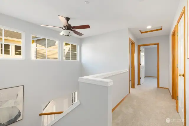 The bright and open hallway leads you through the upstairs, featuring beautiful windows and updated lighting for a welcoming feel.