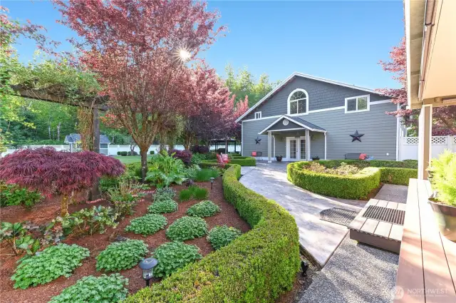 A beautifully stamped concrete walkway leads to the perfect shop, complete with guest quarters, offering both functionality and a private retreat for visitors.