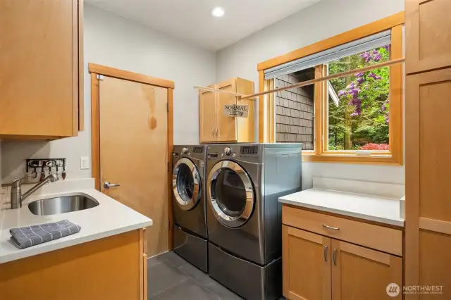 The spacious utility/mudroom features a utility sink, and abundance of cabinet space and folding table.