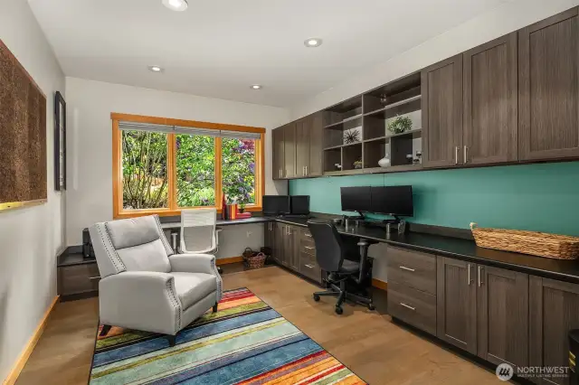 A large main-level den/office with French doors and features built-in desk and cabinet space.