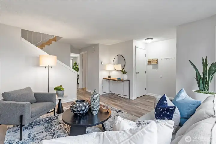 Another view of the living room showing the front entry, coat closet and the powder room off the hallway.