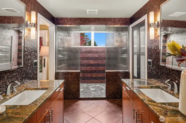 Every day is spa day with this tiled 5-piece bathroom featuring a jetted soaking tub, waterfall shower, sconce lighting, and radiant heated floors.